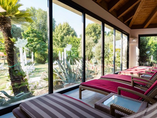 Hotel in Montegrotto Terme: the Garden Terme Lounge chairs facing green garden through large glass windows